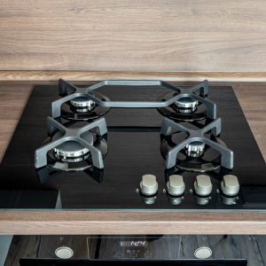 A modern gas cooker with ceramic hob, electric oven and a dark brown wooden kitchen ready for cooking a meal from a top view with reflections
