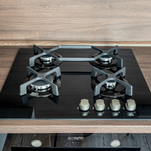 A modern gas cooker with ceramic hob, electric oven and a dark brown wooden kitchen ready for cooking a meal from a top view with reflections