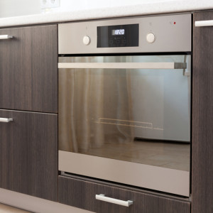 Kitchen cabinets with metal handles and built-in electric oven.